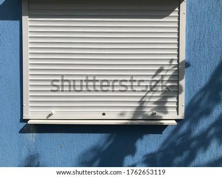 background texture of a white closed plastic window with a rollet on a blue wall background
