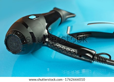 Hair clipper and hair dryer on a blue background. Tools on a glass table.