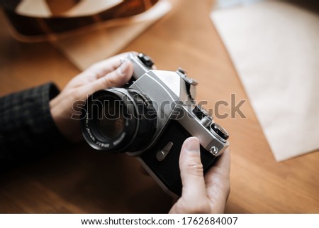 Vintage film camera in the man hands on a wooden background. horizontal. top view