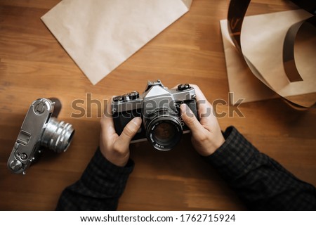 man hands holds retro camera on a wooden table. Vertical. Top view