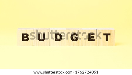 word budget made with black letters on small wooden blocks on yellow background at bright light closeup