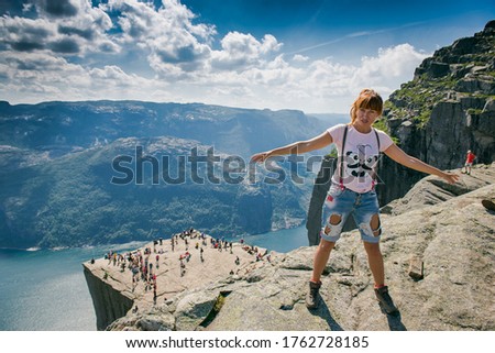 Happy girl traveler. Girl on the background of the sights of Norway. Tourist girl in a jump. 