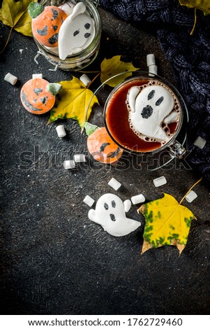 Funny idea for Halloween party, hot chocolate with decorative with marshmallows in shape of a ghost, pumpkin, monster, eyes,dark background copy space
