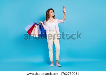Full length body size view of her she nice attractive lovely cheerful wavy-haired girl carrying new things taking making selfie having fun isolated on bright vivid shine vibrant blue color background