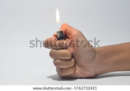 Cropped Hand Igniting Cigarette Lighter Against White Isolated Background  Royalty-Free Stock Photo #1762732421