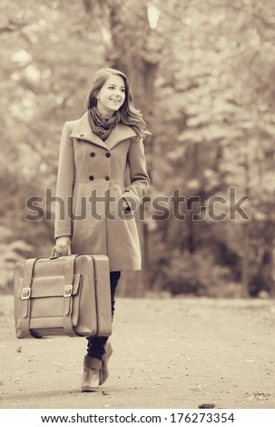 Girl with suitcase at autumn outdoor. Photo in old color image style.