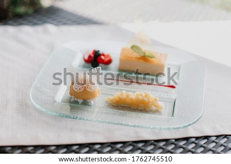 top view A beautifully sorted dish decorated with a butterfly made from pieces of fruit and a biscuit dessert and corn and a mint leaf on a transparent plate and white table