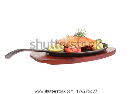 healthy sea food: grilled salmon on iron pan over wooden plate with lemon avocado and tomatoes isolated on white background