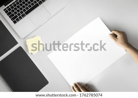 Old hand holding paper at office table with computer and book paper note, Top view with copy space.