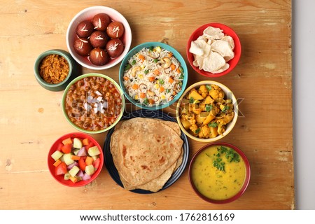 Indian whole meal with yellow dal, vegetable pulao, chapati,gulab jamun, salad, papad, pickle, chana masala curry and aloo gobi Royalty-Free Stock Photo #1762816169