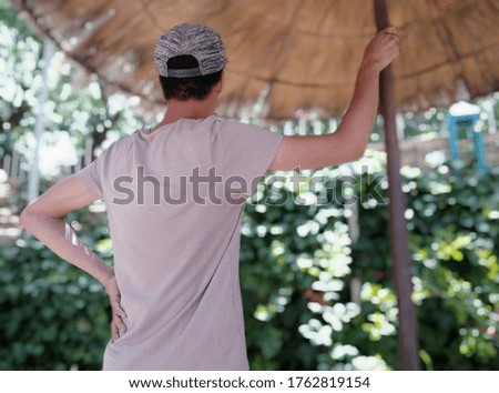 Picture of a person under a sun deck in the park meditating and enjoying the beauty of green plants on a sunny day