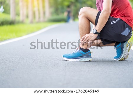 Young adult male with his muscle pain during running. runner man having leg ache due to Ankle Sprains or Achilles Tendonitis. Sports injuries and medical concept Royalty-Free Stock Photo #1762845149