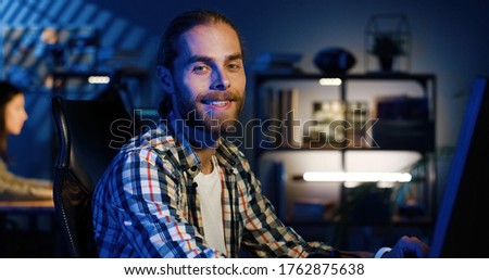 Portrait of professional video editor editing video on his personal computer with two displays in modern video studio. Young man works with headphones