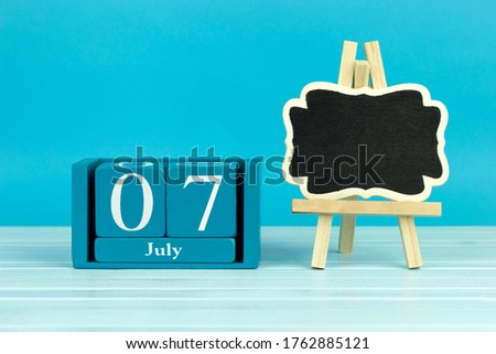 wooden calendar with the date of July 7 and an easel on a blue background, place for text, 
International Chocolate Day