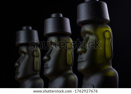 Green and yellow color humanoid moai sculpture isolated on black background
