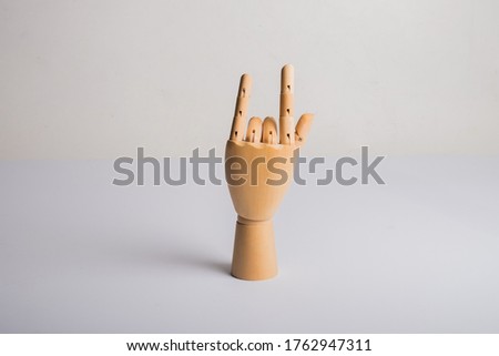 wooden hand displaying devil horns isolated on white background