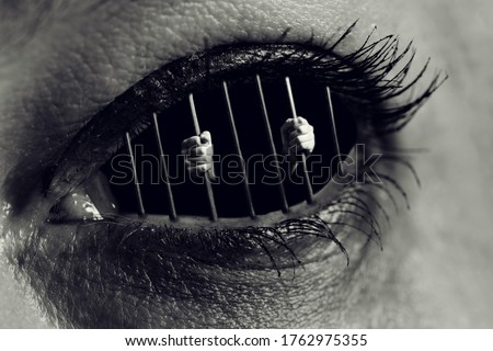 Conceptual monochrome photo of hands holding the bars of a prison inside a human eye Royalty-Free Stock Photo #1762975355