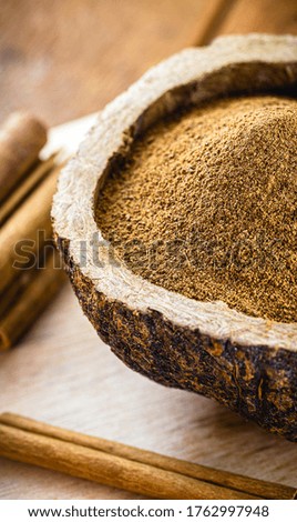 powdered cinnamon in a rustic bowl, with pieces of cinnamon in the shell around, a culinary spice in a rustic photo.