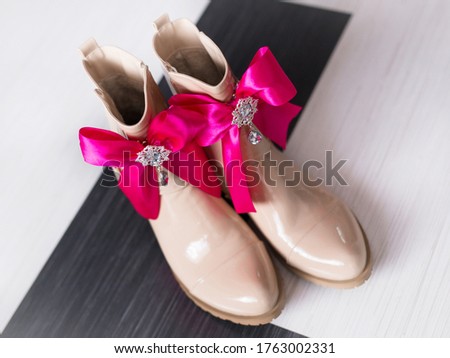 beige shoes with a brooch and pink bows on a black and white background
