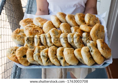 Woman holding a tray with ready to traditional, homemade East European pies with vegetables.