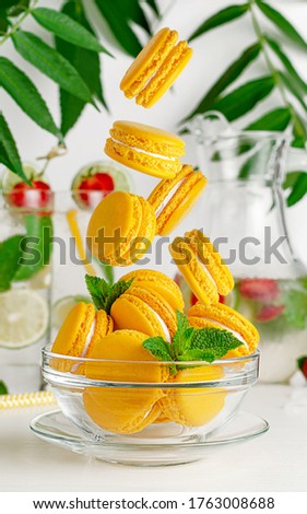 Yellow macaroons falling into the glass bowl. French dessert concept
