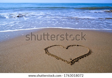 a painted heart on wet sand with a blurred background of sea waves