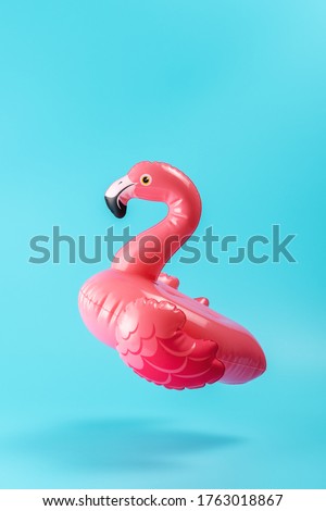 Inflatable pool toy flamingo on a blue background. Minimal summer concept.