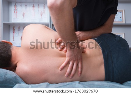 Photo of physical therapist making deep or kinesio massage on a mans back.
