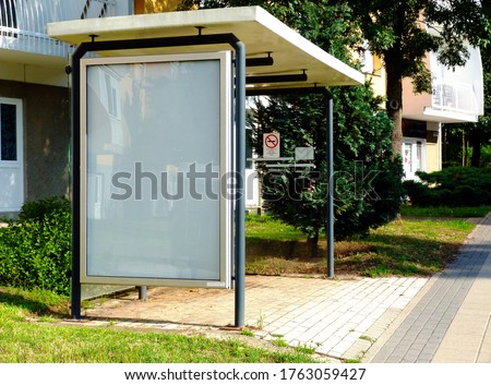 image composite of bus shelter at bus stop of blank light box and glass structure. park like urban setting. green background. safety glass design. white poster ad commercial poster space display glass