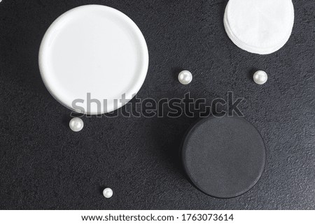 white and black jar cosmetic for bath cotton pearl disks on a black table. Copyspace. mockup. top view. flat lay