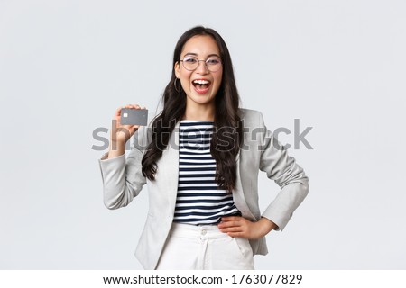 Business, finance and employment, entrepreneur and money concept. Laughing cheerful and outgoing female office manager in white suit and glasses showing credit card