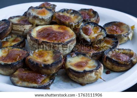 Baked with butter and cheddar mushrooms in plate on the dark surface