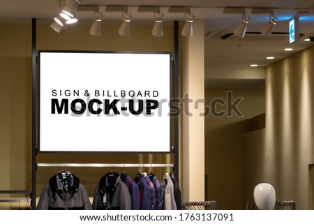 Mock up blank horizontal signboard with clipping path on showcase of winter cloths showroom in shopping mall, empty space for insert advertising graphic or text information 