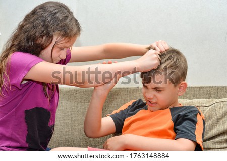 An angry and cruel older sister scolds her brother and grabs his hair, social problems of raising a family with children. Royalty-Free Stock Photo #1763148884