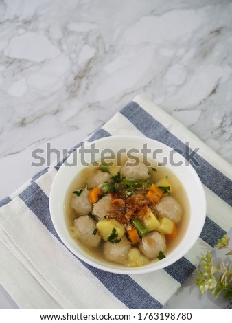 meat ball soup on the white bowl, isolated and white background. the soup is consist of carrot, meat balls, bean, potatoes, with chicken stock, salt and pepper.