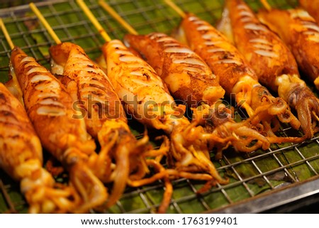    Pictures of grilled squid, street food at night in Thailand                            