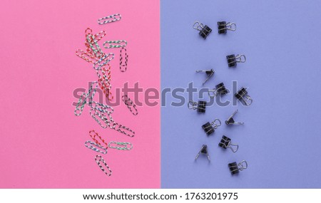 Lot of paper clips on a purplish-pink background. Top view. Minimalistic office concept