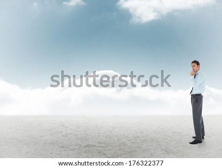 Thoughtful businessman with hand on chin against cloudy sky background