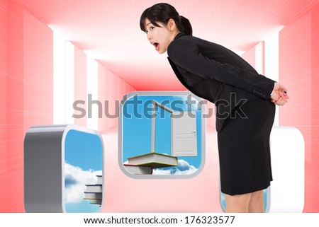 Surprised businesswoman bending against bright red room with windows