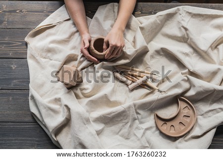 Female potters hand making clay pottery at the table with a different wooden tools close up.