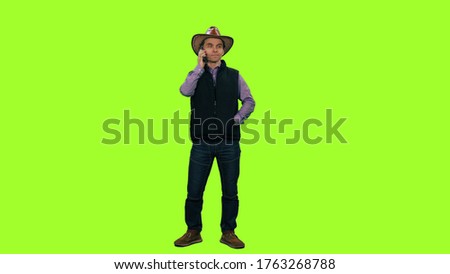 A man in cowboy hat standing and talking on the phone, 4k footage on clean green background