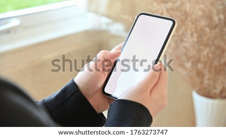 Close up image of female hands using smartphone with blurred background.