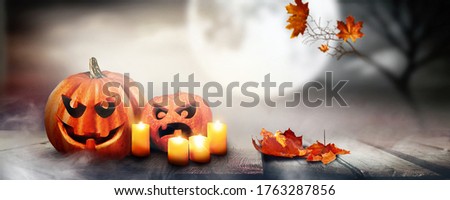 Beautiful background for Halloween. Glowing pumpkins and candles against background of dark night Mystical sky with full moon and fog. Ultra wide format.