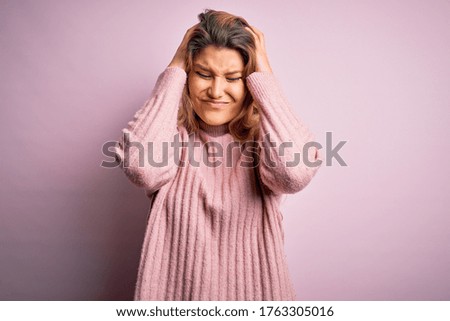 Young beautiful blonde woman wearing casual pink sweater over isolated background suffering from headache desperate and stressed because pain and migraine. Hands on head.
