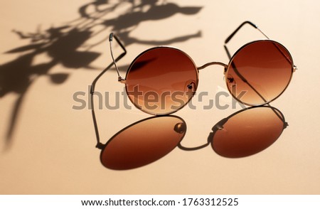 Brown sunglasses in a round shape. Bright sunlight. Contrasting shadows.