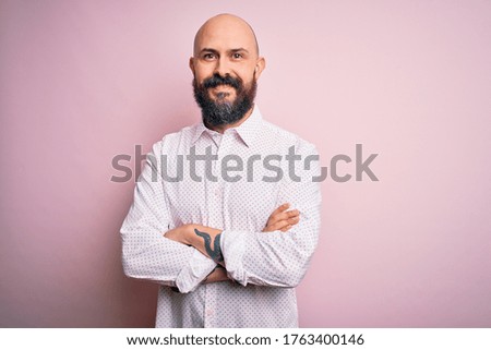 Handsome bald man with beard wearing elegant shirt over isolated pink background happy face smiling with crossed arms looking at the camera. Positive person.