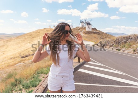 Blonde girl white dressed dancing. Traditional windmills in the background.