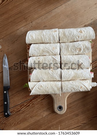 A top view of lavash wraps on a wooden table next by a knife