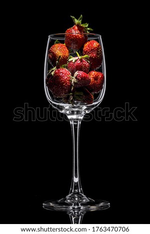 Fresh strawberries in a glass on the table. Ripe strawberries closeup. Sweet summer crop. Juicy dessert. Healthy food. Red berries in a glass vase on a black background. The concept of freshness.