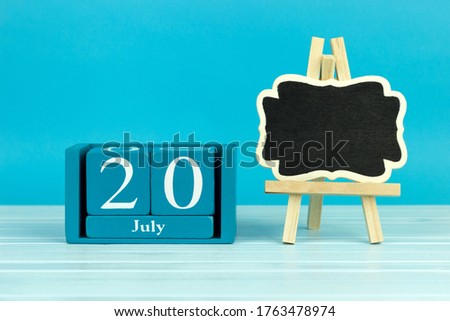 wooden calendar with the date of July 20 and an easel on a blue background, place for text, 
International Chess Day, International Cake Day